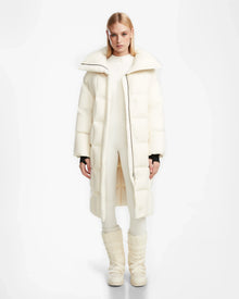 A person wearing the Rudsak SASH - 8124536 Iceland off-white women’s down puffer coat, matching pants, and tall padded boots stands against a plain white background, facing forward with a neutral expression.