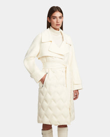 A woman stands with one hand in her pocket, modeling the Rudsak ZOE - 8124711 Iceland off-white quilted down trench with a wide collar, belted waist, and double-breasted buttons against a plain background.