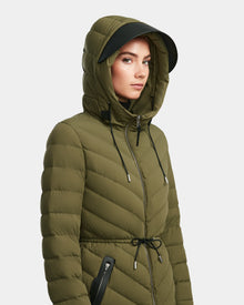 A woman stands against a white background wearing the Rudsak FRANCINE - 8124722 Loden Green puffer jacket, featuring RDS-certified down, a hood, black zippers, and a drawstring waist.