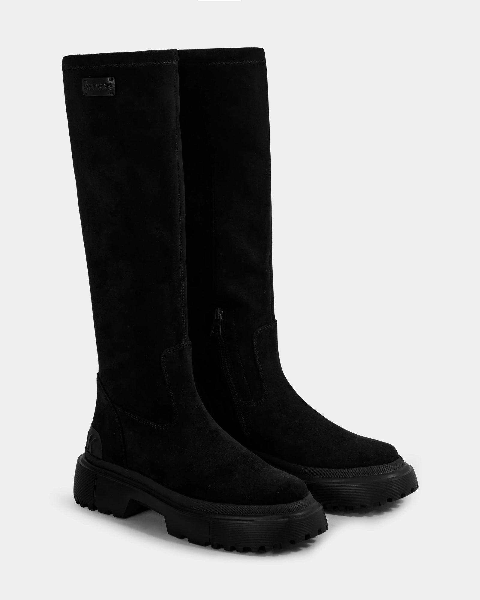 AVOLA - L225514 Black women’s knee-high boots by Rudsak in tall faux suede, featuring chunky lug soles and side zippers, shown on a plain light gray background.