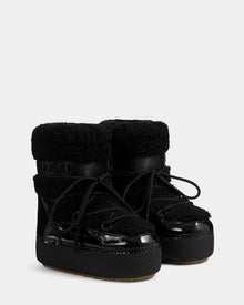 The Rudsak KATHY Y - 1224500 Black boots feature thick textured soles, shiny patent leather details, fuzzy faux fur uppers, round toes, black laces, and a cozy insulated look inspired by classic moon boots.