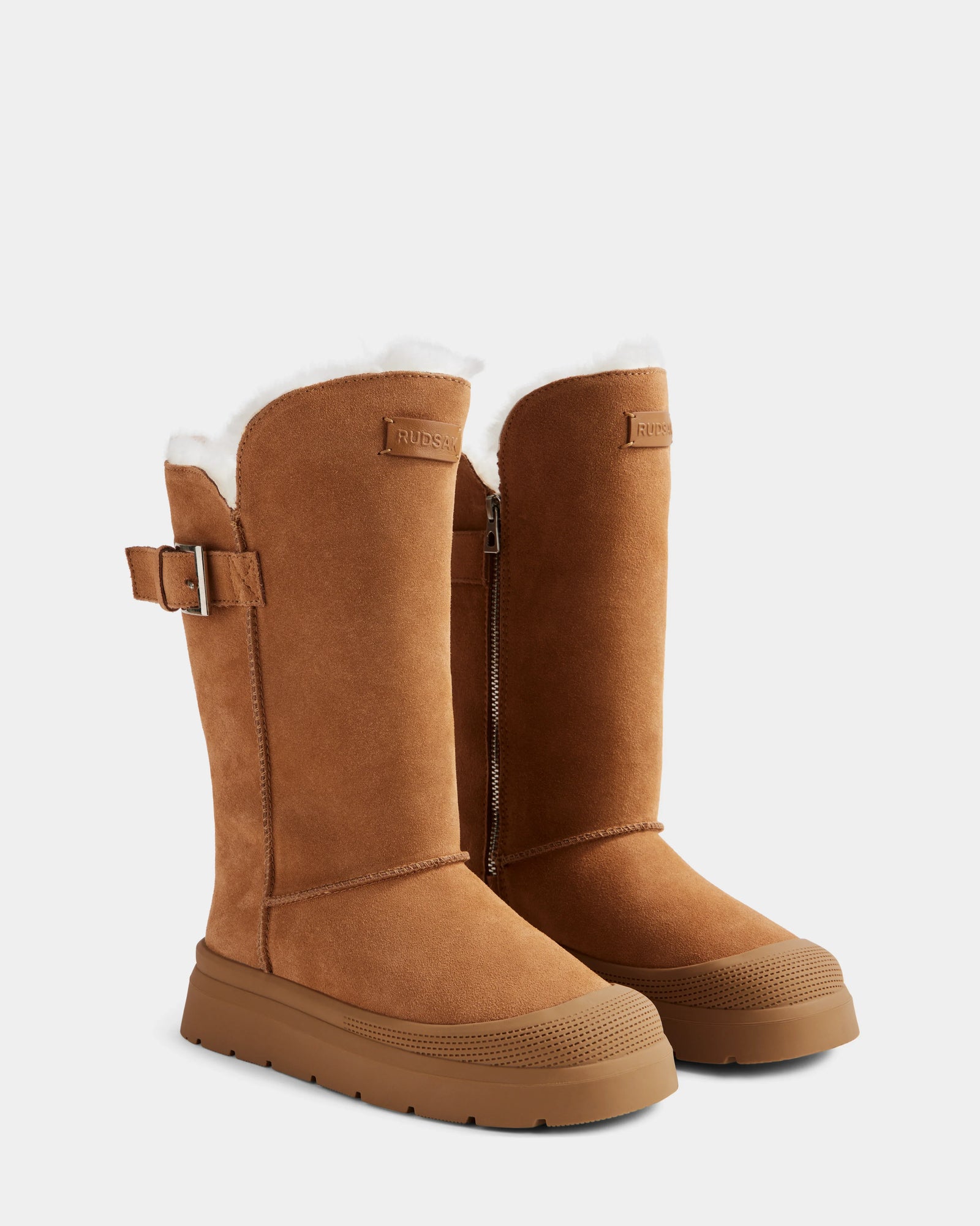 The Rudsak KLAIR - L225027 Tan are tall women's winter boots in suede with wool lining, side buckles, zippers, and textured rubber soles—perfect for cozy winter style.