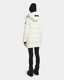 A person wearing the Rudsak MIRIAM - L123544 Iceland womens white down puffer coat with RDS-certified down, black leggings, boots, and a black knit beanie stands facing away from the camera against a plain light background.