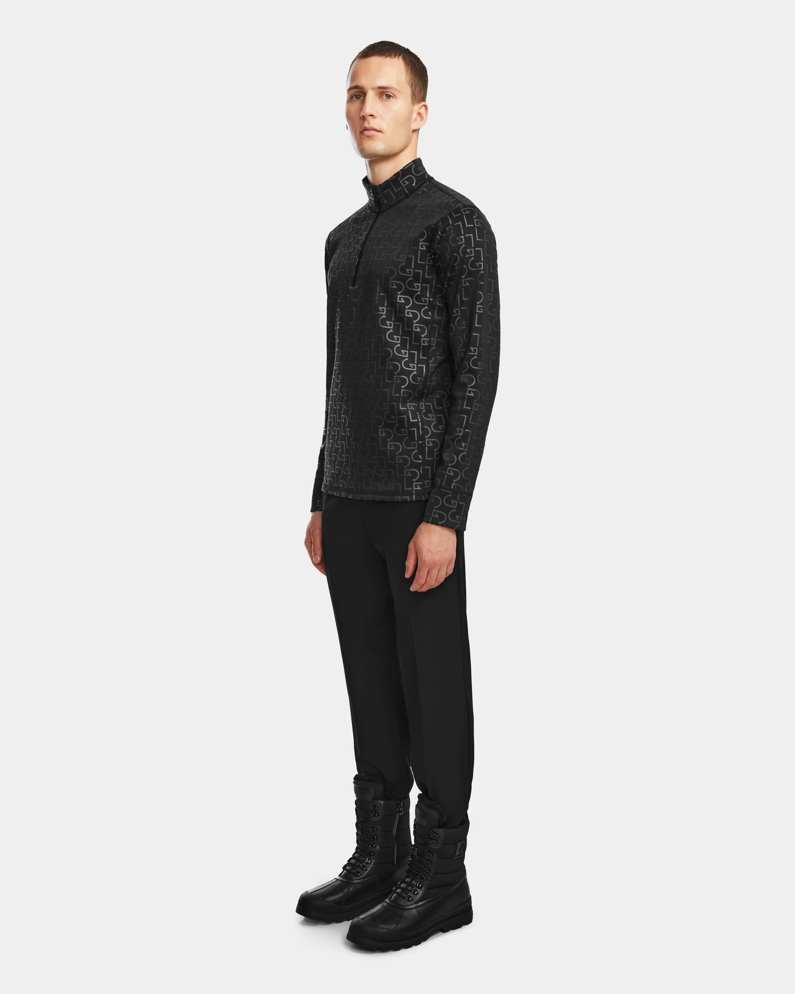 A man stands against a white background wearing the Rudsak ROMEO - 6524525 Black jacket, black pants, and black boots, looking straight ahead with his arms relaxed by his sides.