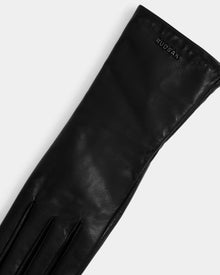 The TORRI - L425544 Black by Rudsak is a long women’s leather glove with subtle stitching, an embossed logo near the cuff, and a wool-cashmere lining, displayed against a plain white background.