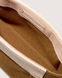 A close-up of a brown woolen tote bag with white leather trim by Graf Lantz, crafted from sustainable Merino wool. The interior features detailed white stitching for contrast, and the minimalist design exudes elegance similar to their Frankie Merino Wool Clutch.