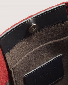 Close-up view of the inside of a red Graf Lantz felt pouch featuring a black leather flap with snap button closure, visible stitching, an inner pocket, and a black leather label.