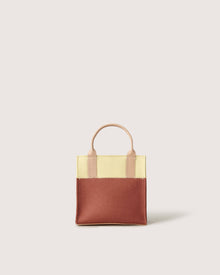 A small Graf Lantz two-toned mini tote handbag features a yellow upper section, a brown lower section, and a short beige handle against a plain light background.