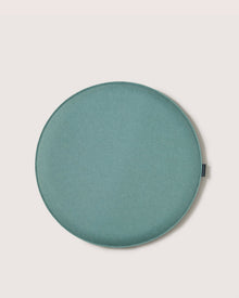A round, flat, teal fabric cushion by Graf Lantz, this stylish seat is ideal as a meditation or Zabuton Seat Cushion, displayed on an off-white background.