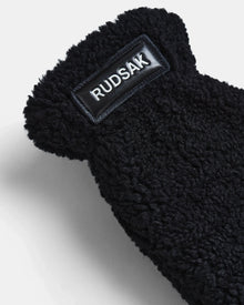 Close-up of SUSAN S - 8423511 Black by Rudsak, showing black textured fleece-like fabric with a rectangular brand patch—ideal for women’s teddy faux fur mittens.