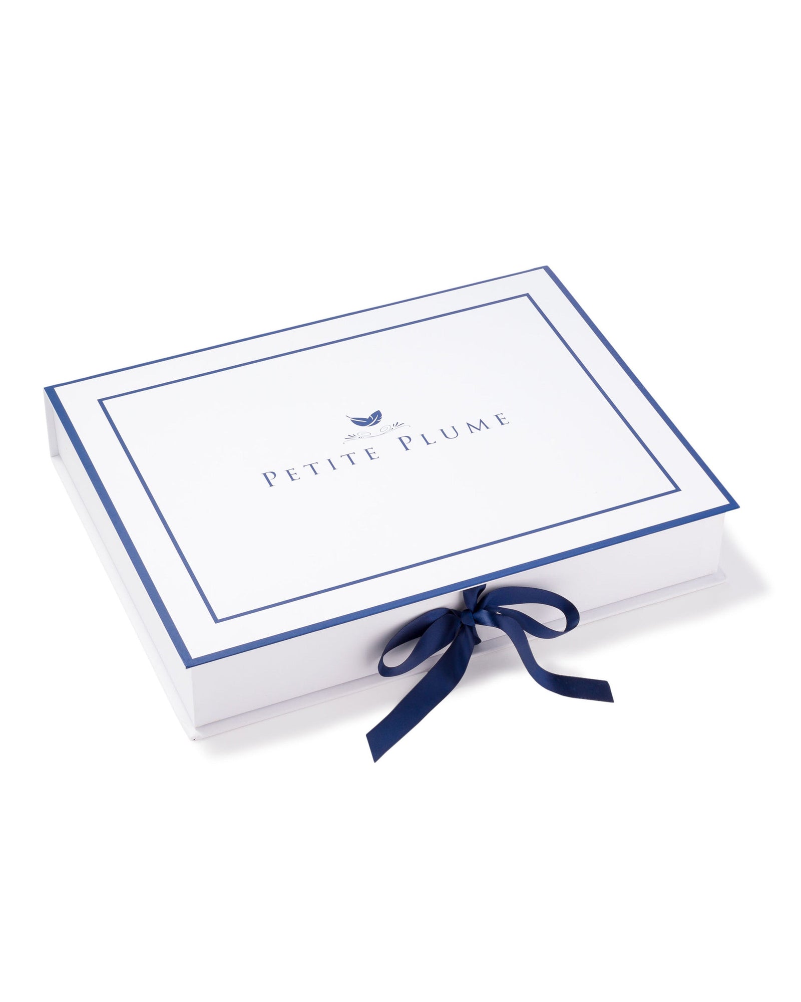A rectangular white box with a navy border features Petite Plume on top and a closed navy ribbon bow, reflecting the elegance of the Womens Silk Cami Short Set in White Art Nouveau.