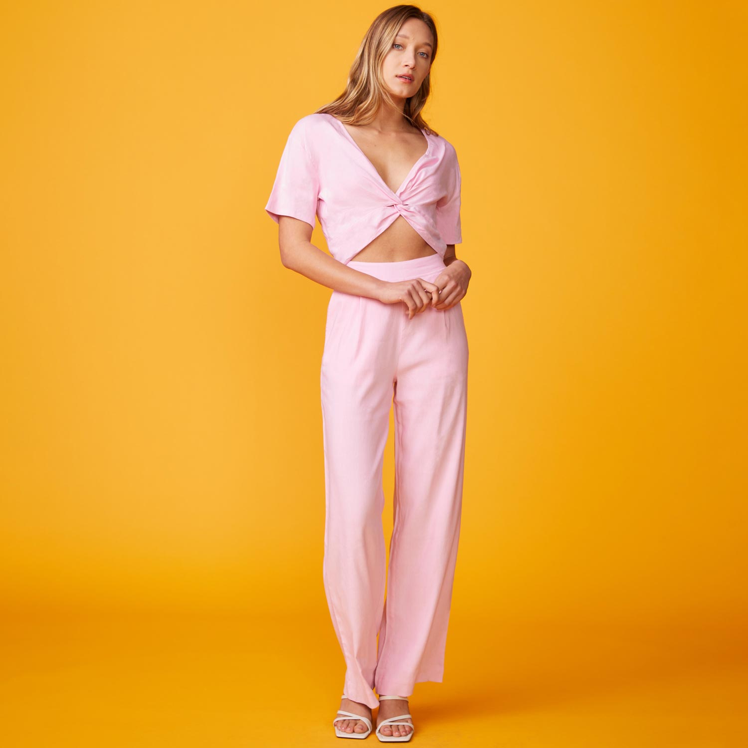 Front view of model wearing the linen pleated pants in bubble gum. 