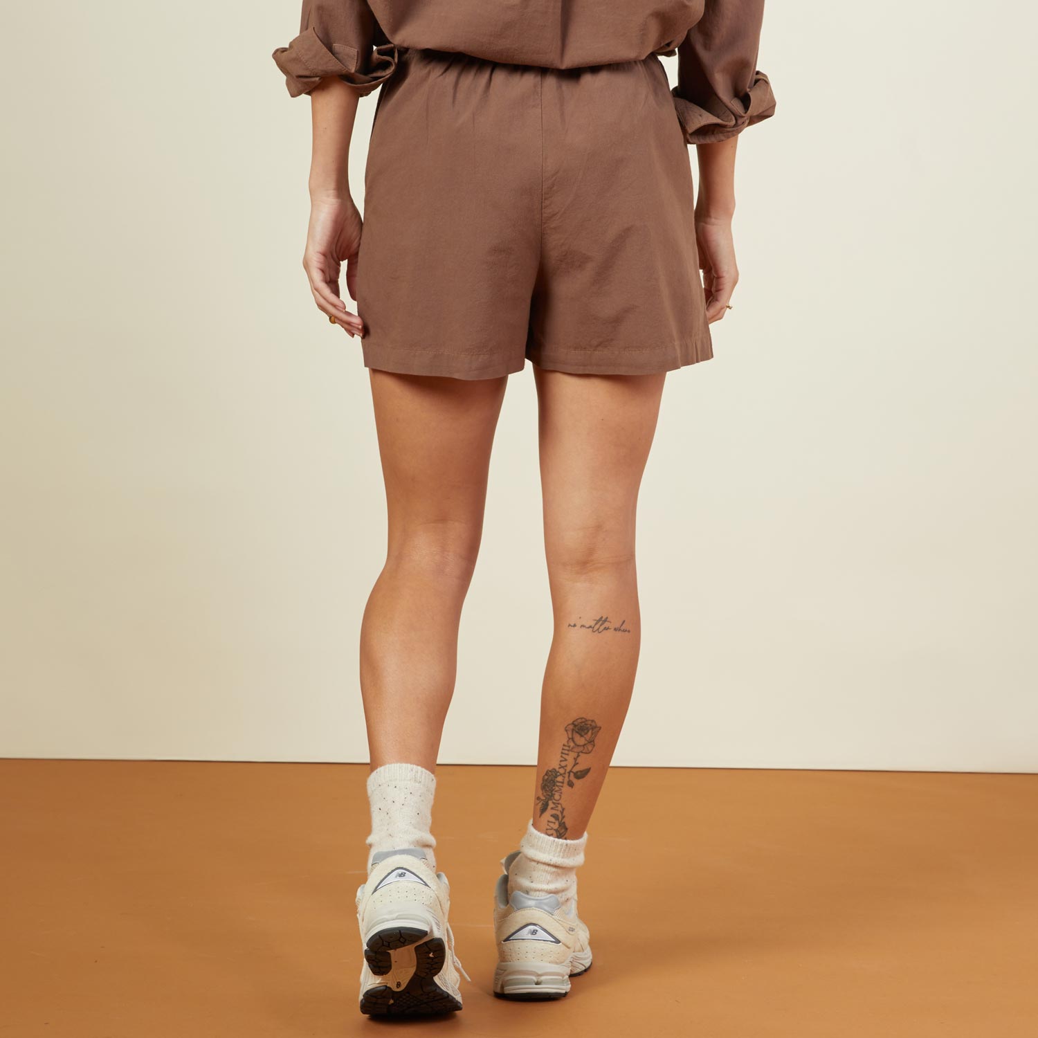 Back view of model wearing the poplin shorts in dusty cocoa.