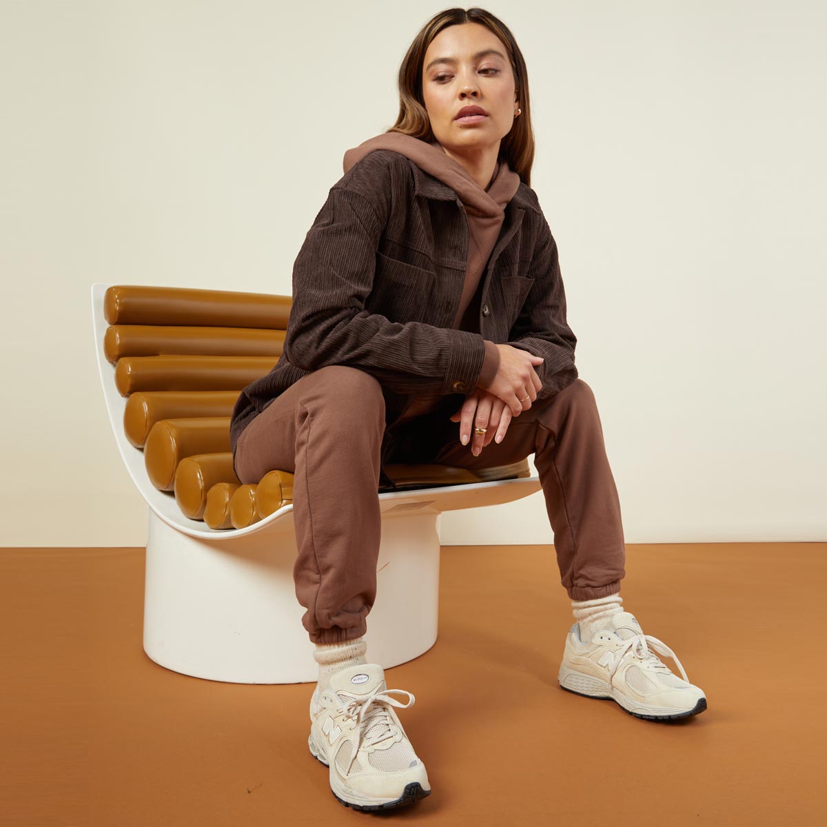 Front view of model sitting while wearing the corduroy shacket in dark oak.