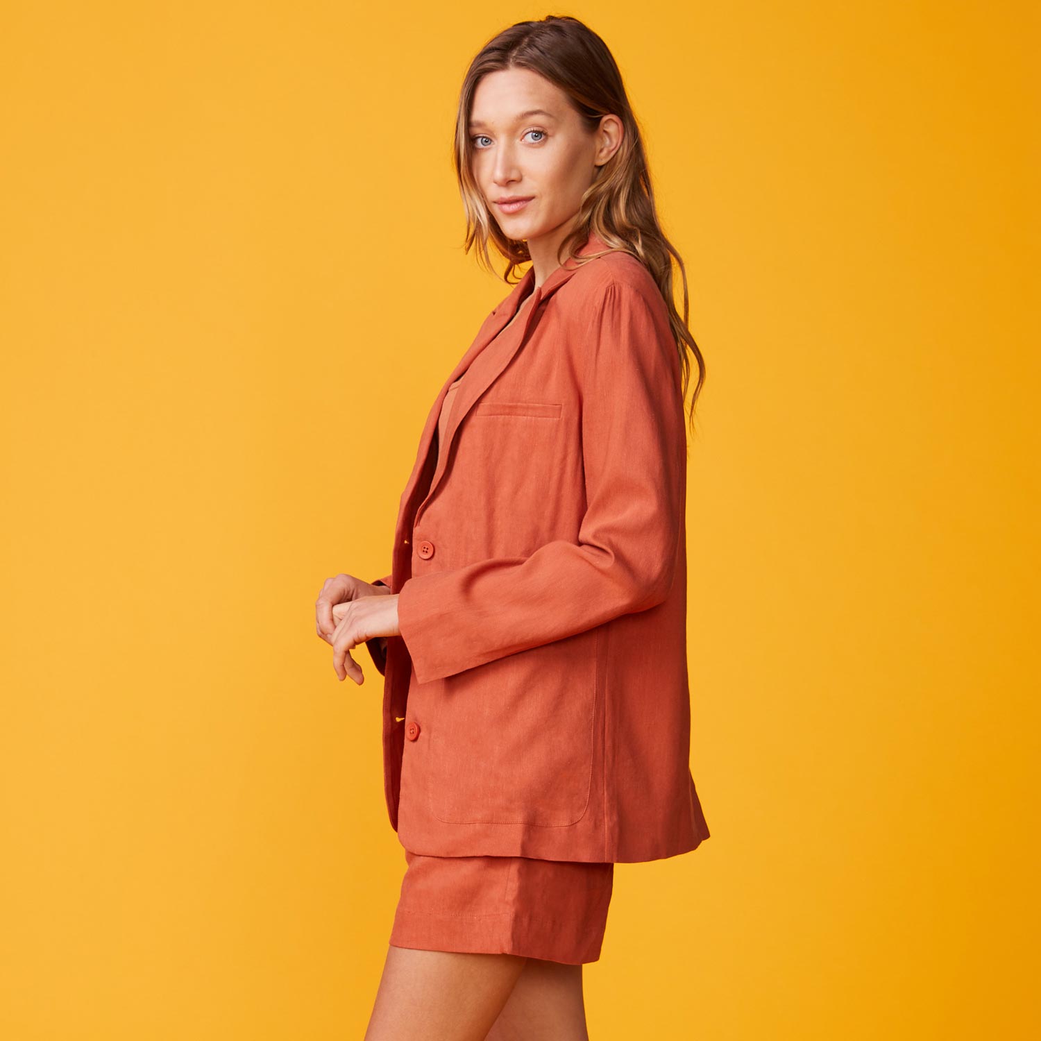 Side view of model wearing the linen oversized blazer in faded rust.