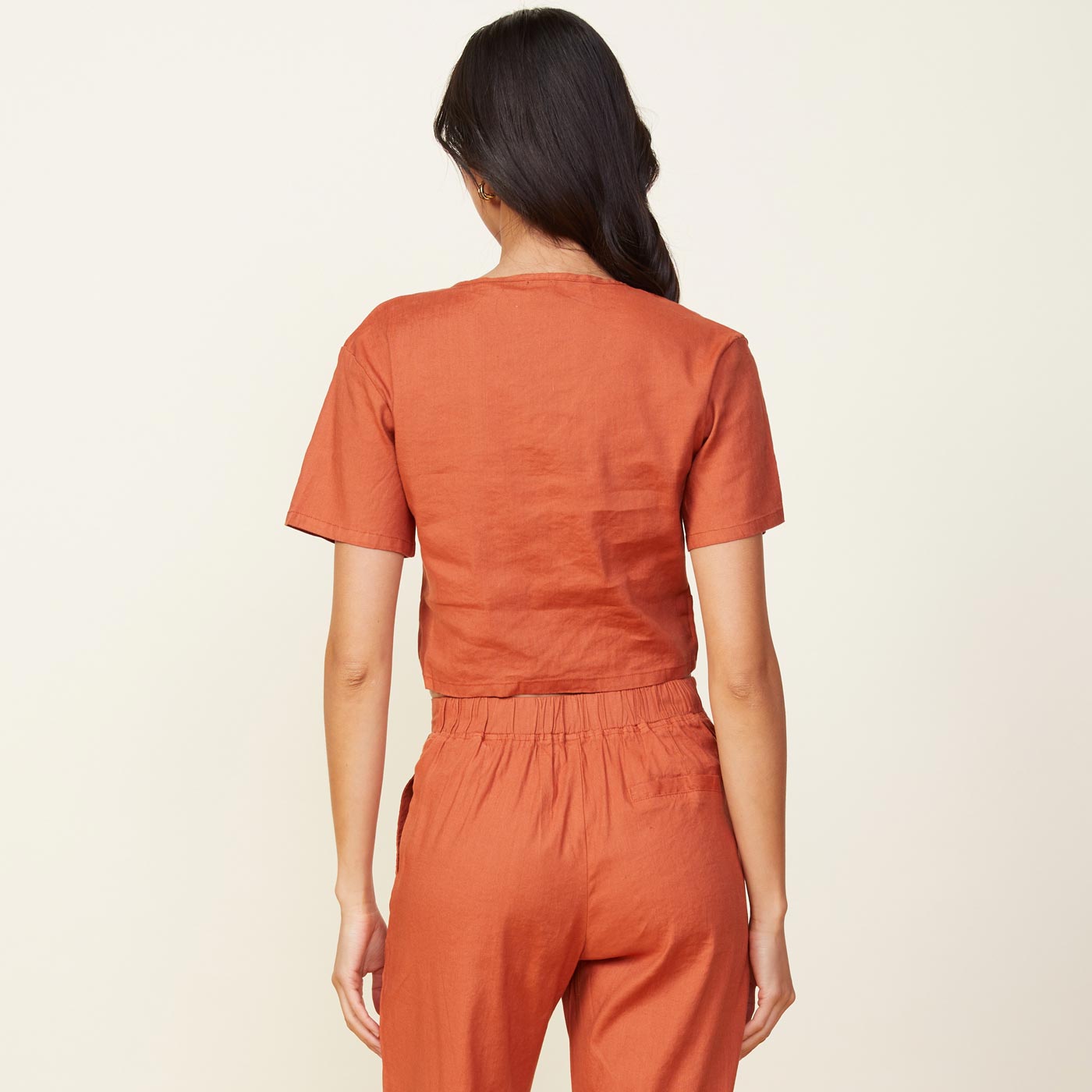 Back view of model wearing the linen front twist top in faded rust.