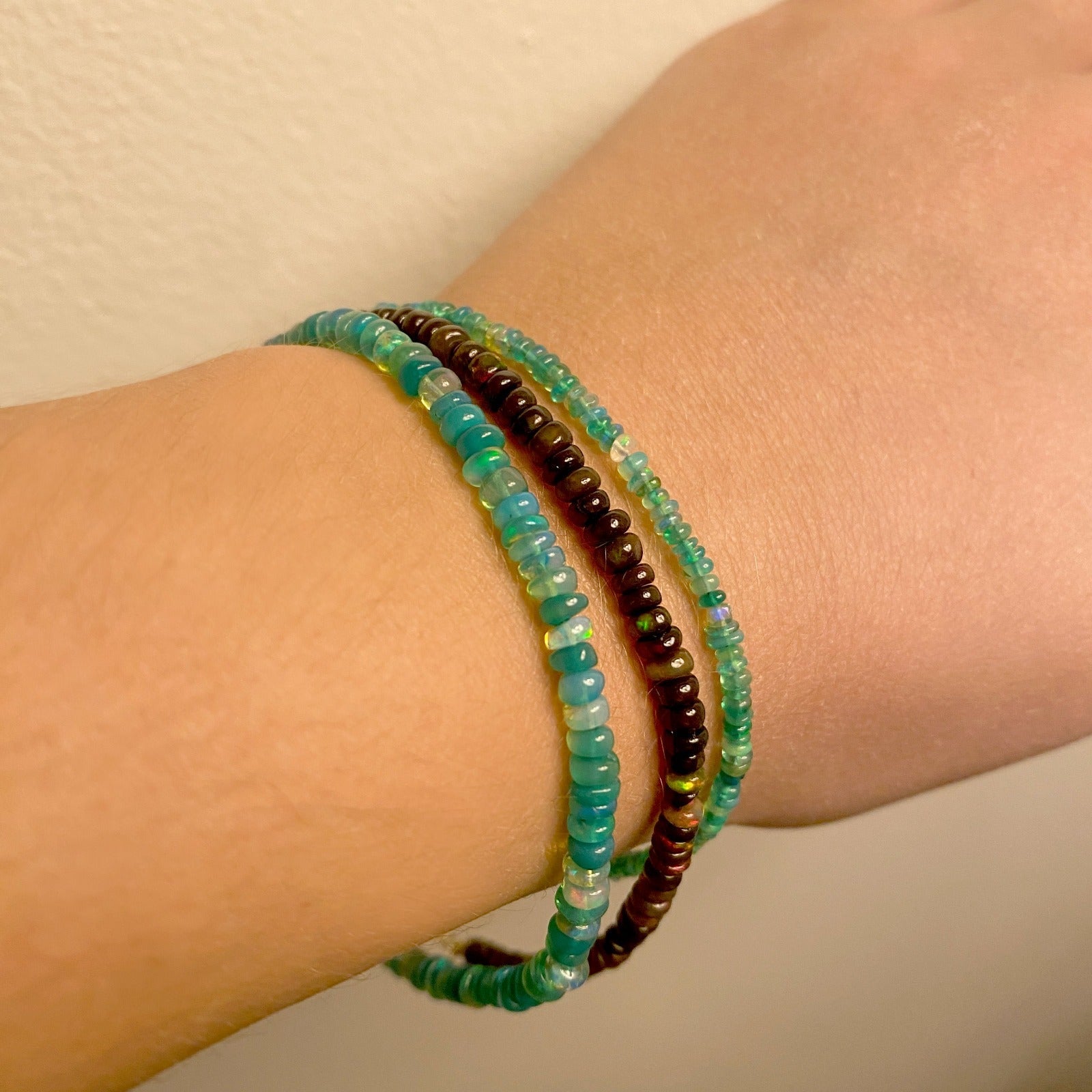 Shimmering beaded bracelet made of smooth opals in shades of green on a gold linking lobster clasp.