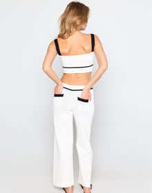 Woman wearing a white outfit with black accents on a plain background
