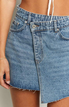 Close-up of the light blue denim mini skirt showing the asymmetrical wrap front and frayed hem