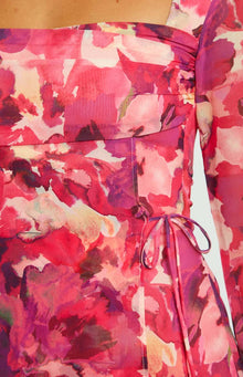 Side-back view of a pink floral print long sleeve mini dress with a fitted waist and flowy skirt