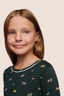 Model is wearing Kids Printed TENCEL Modal Unisex Long PJ Set  in Holiday Dogs Pine/Ivory