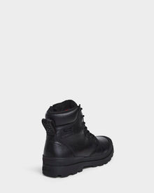 The Rudsak ARTUR - M223501 Black men's ankle boot, crafted from weather-treated leather, is shown angled on a white background, featuring a rugged sole and embossed branding for stylish durability.