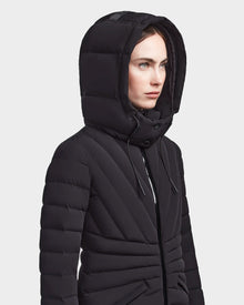 A person wears the HANNA - 8123562 Black winter down jacket by Rudsak, featuring a hood and RDS certified down. Shown from the waist up, they look to the side against a plain light background.