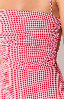 Close-up of the side ruching and cutout detail on the red and white gingham mini dress