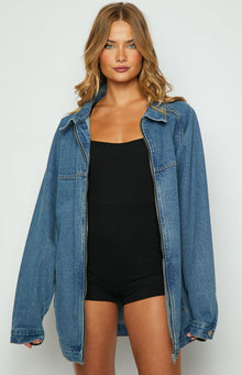 Front view of an oversized blue denim jacket with a collar and long sleeves, partially unzipped