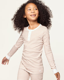 Kid's Pima Snug Fit Pajama Set in Camel Stripe features a beige and white striped long-sleeve top with white cuffs and button placket, plus matching pants with white ankle cuffs.