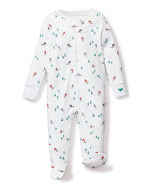 The Petite Plume Babys Pima Romper in Apres Ski is a white onesie crafted from soft Pima cotton, featuring a zip-up front, long sleeves, enclosed feet, and charming skier and evergreen tree patterns in green, blue, red, and purple for extra warmth.