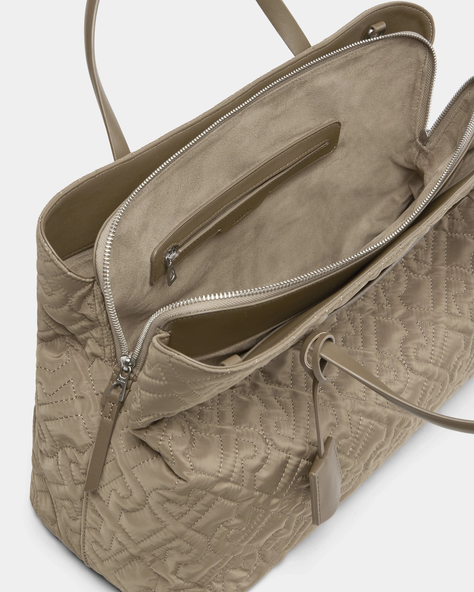 The Rudsak ASMINE - L325005 Almond is a taupe quilted monogram tote with double handles, a spacious suede-like lined interior, an inner zip pocket, and an exterior hanging tag.