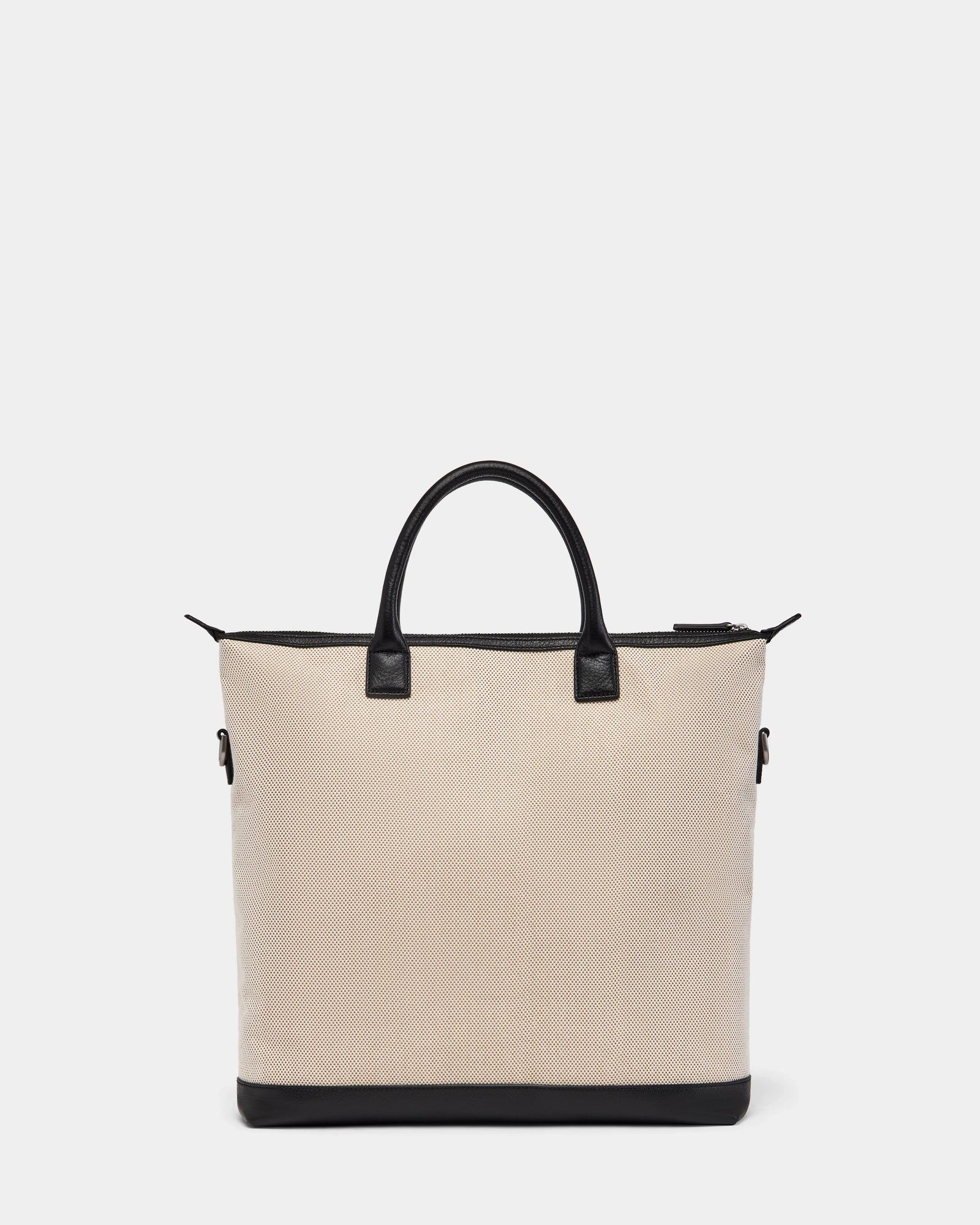 The Rudsak DEXTER - 9324513 Vanilla is a beige canvas tote with black leather handles, trim, and base. Its zippered top and rectangular shape make this unisex bag a versatile accessory for any occasion. Displayed on a plain white background.