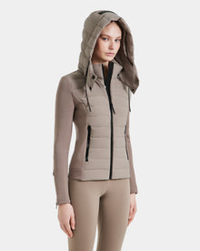 A woman wears the Rudsak MABS - 8124825 Cement lightweight short taupe jacket with a hood and front zipper, paired with matching taupe leggings, standing against a plain white background.