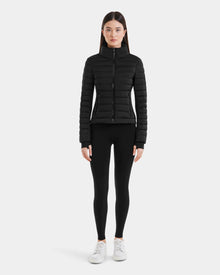 A woman stands confidently in the Rudsak MARYA M - L123559 Black, a wind- and water-repellent women’s down puffer jacket made with RDS certified down.