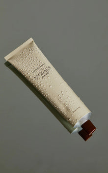 Beige tube labeled NOGLASS the polish and LUX UNFILTERED with water droplets and brown cap, 60 ml / 2 fl oz