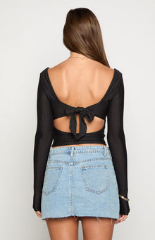 Rear view of a black long sleeve top with a tie-back detail and cutouts at the waist