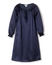 The Girls Silk Delphine Nightgown by Petite Plume is a navy blue sleepwear adorned with white polka dots, featuring long sleeves, a ruffled neckline with a tie, and slightly gathered cuffs.