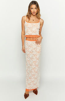 Front view of a white floral lace midi skirt with an orange contrast lining and straight fit
