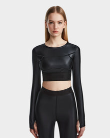 A woman with straight, light brown hair wears the Rudsak LORA - 8524026 Black fitted long sleeve top and matching high-waisted leggings, standing against a plain white background.