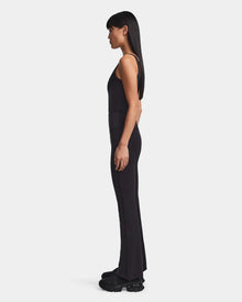 A woman stands in profile facing left, wearing a fitted black sleeveless top and Rudsak ADRIANA - 8523550 Black flared-leg leggings with black sneakers, against a plain light gray background.