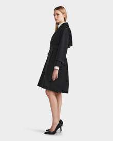 A woman in the MIRELLE - 8124055 Black trench coat by Rudsak, featuring a tailored silhouette perfect for versatile styling.
