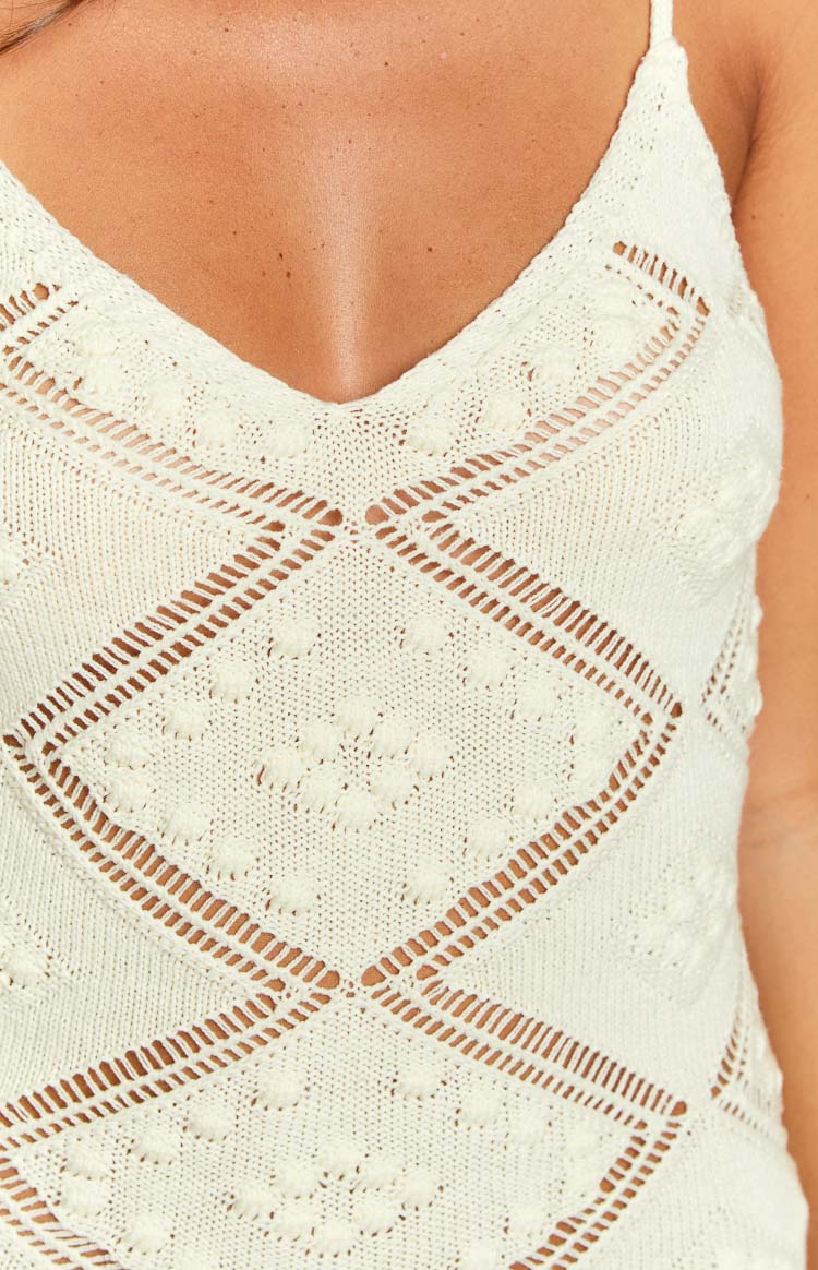 Close-up of the cream knit mini dress showing the V-neckline and diamond pattern with bobble stitches and openwork