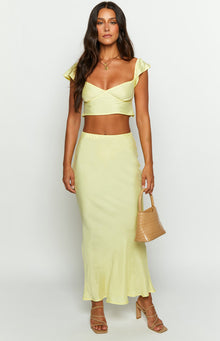Full length view of a light yellow satin maxi skirt with a smooth, flowing drape