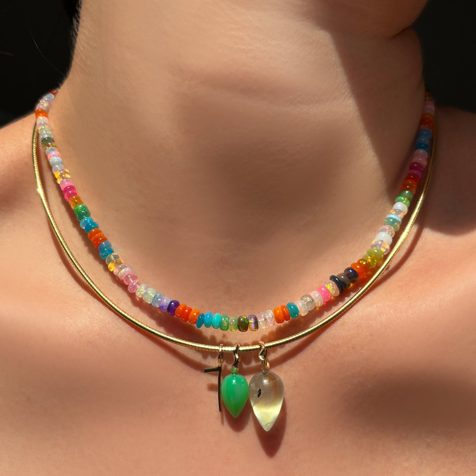 desert disco opal necklace with omega chain and quill number charm, prehnite drop charm, chrysoprase drop charm on the neck.