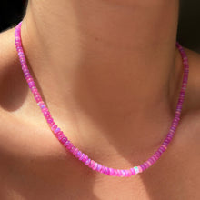  Shimmering beaded necklace made of faceted opals in shades of pink and fuchsia on a gold linking ovals clasp styled on a neck  