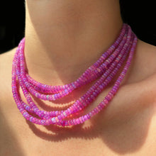  Shimmering beaded necklace made of faceted opals in shades of pink and fuchsia on a gold linking ovals clasp styled on a neck layered together