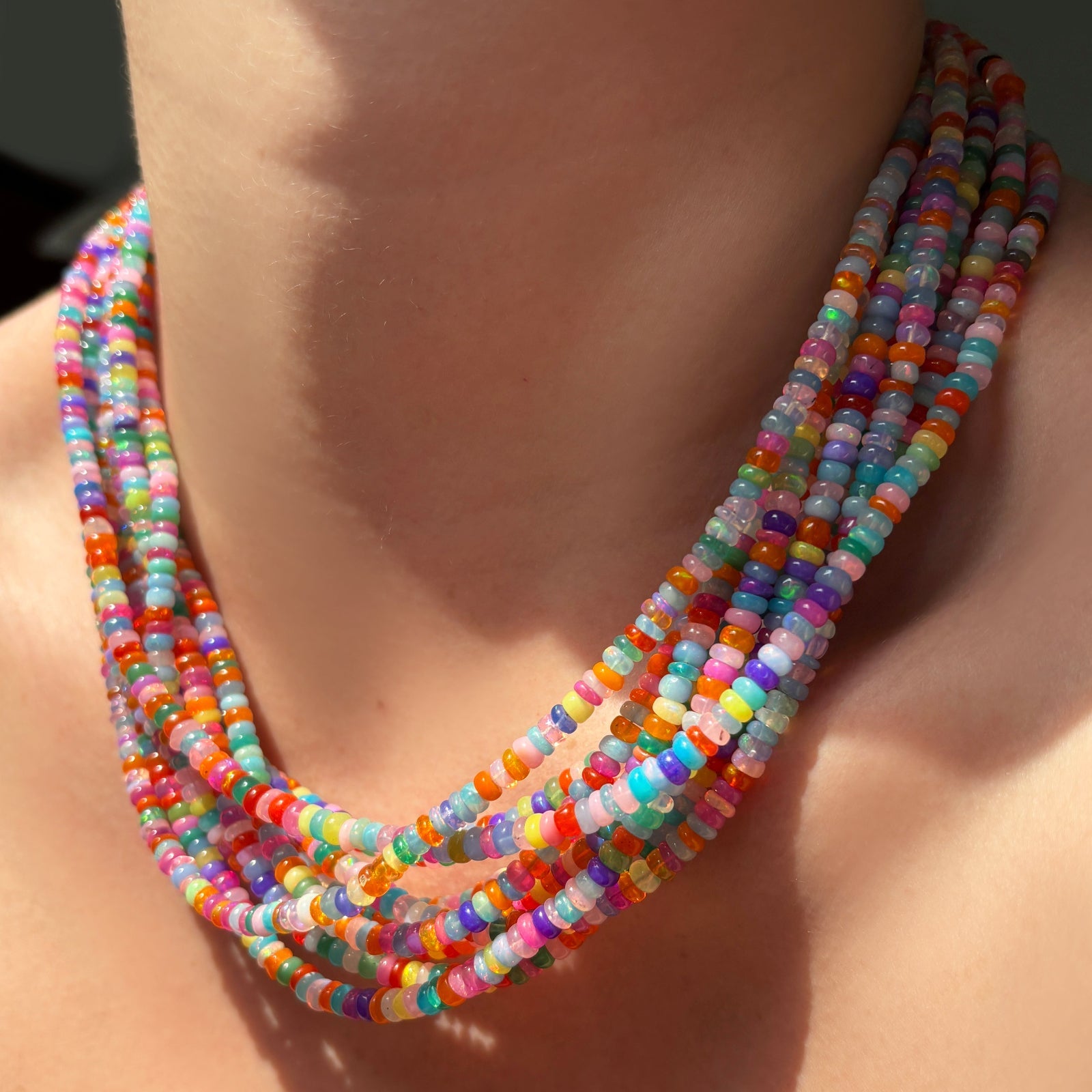 High-biscus multi-colored opal necklaces layered on the neck.