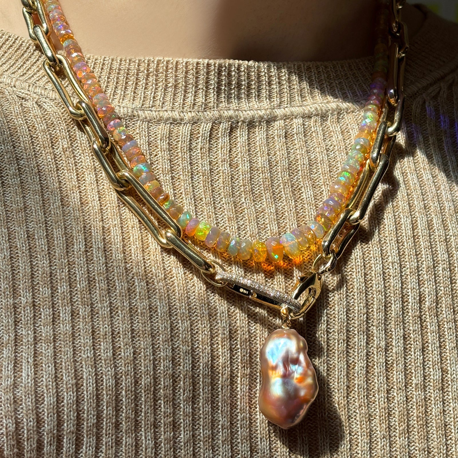 mercury in retrograde opal necklace with molten link chain necklace, oval pave charm lock and blush baroque pearl charm over a neutral knit sweater.