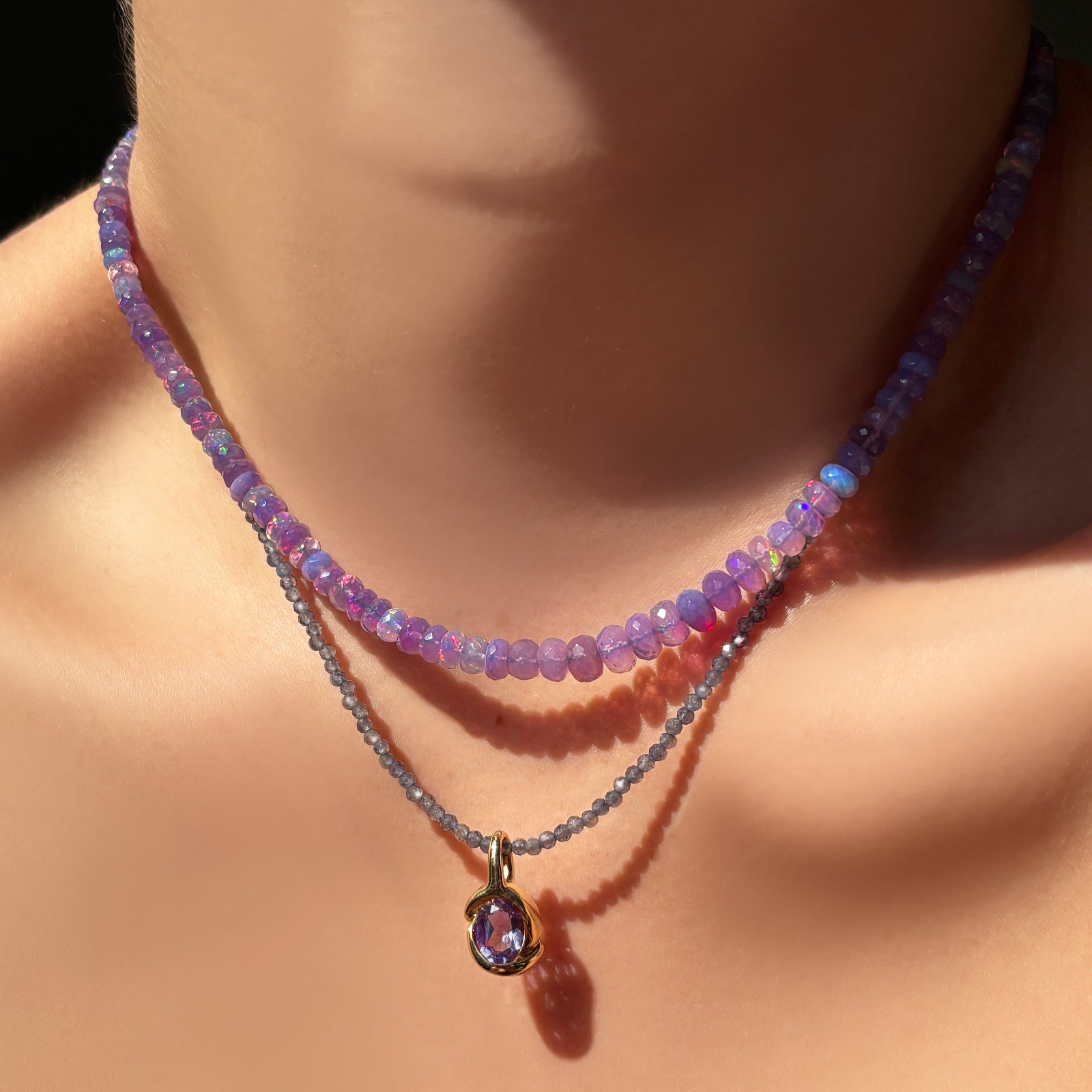 Necklace with an amethyst pendant on a neck against a dark background